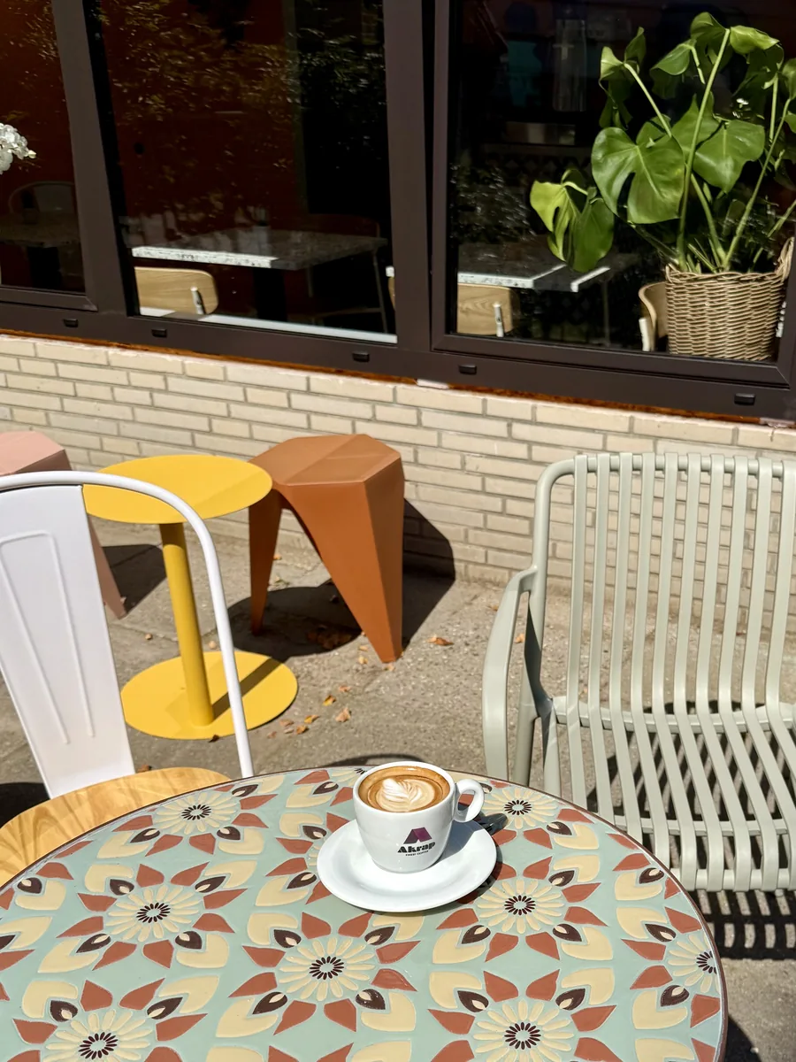 Cappuccino mit Latte Art auf buntem Mosaiktisch im sonnigen Außenbereich des Cafe de Villa Wedel